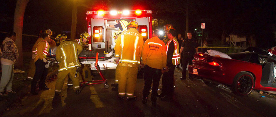 Crews loading a patient into an ambulance at a nighttime traffic collision